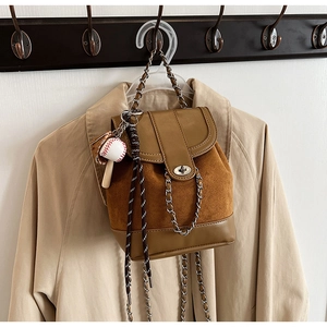 Detail of vintage brown matte backpack with silver chain strap and baseball pendant