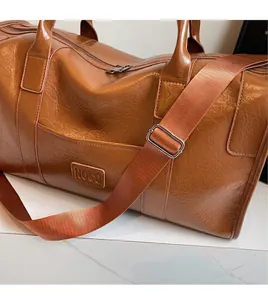 Detalle de bolsa de viaje de cuero PU marrón con correa ajustable y herrajes metálicos