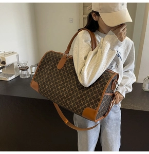 Detailansicht der Reisetasche mit braunem Karomuster und Ledergriffen für Herren