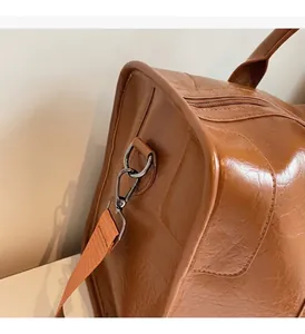 Primer plano del bolso de viaje de cuero marrón con herrajes metálicos y correa tejida