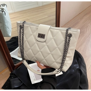 Détail du sac cabas matelassé blanc avec bretelles en chaîne noire et fermoir rotatif