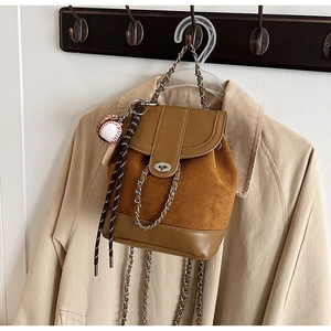 Detail of vintage matte brown bag with chain strap and baseball charm on coat