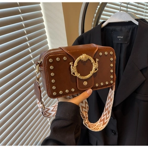 Detailansicht der braunen Ledertasche mit goldener Löwenschnalle und gewebtem Gurt