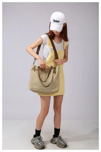 Detailed view of khaki canvas tote bag with brown leather straps shown with casual outfit