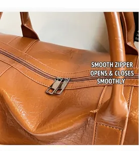 Detalle de las cremalleras metálicas y la textura de cuero sintético marrón del bolso