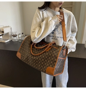 Große Reisetasche mit geometrischem Muster und Lederriemen in einer Café-Umgebung gezeigt