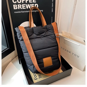 Close-up of quilted black nylon bucket bag with brown leather handles and woven strap