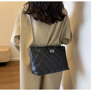 Détail du sac bandoulière en cuir matelassé noir avec chaîne en métal et fermoir rotatif