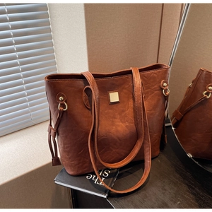 Nahaufnahme der braunen Vintage-Ledertasche mit goldenen Schnallen und schmalen Trägern