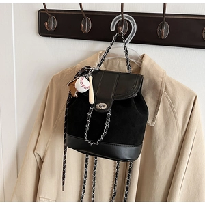 Detail of matte black bucket backpack with silver chain straps and baseball charm