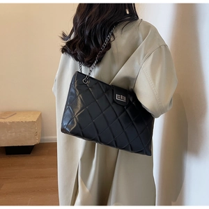 Détail d'un sac cabas noir matelassé avec bandoulière chaîne porté par un mannequin