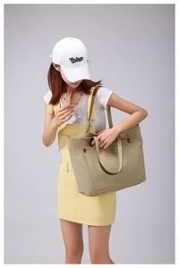 Khaki canvas tote bag detail with brown leather trim and metal zipper pocket