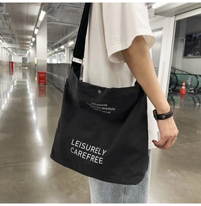 Detail of high-capacity black canvas messenger bag with white LEISURELY CAREFREE text