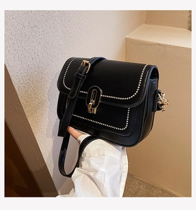 Détail du sac bandoulière noir avec perles dorées et fermoir vintage élégant