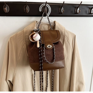 Detail of retro mini backpack in brown matte suede with chain strap and sports charms