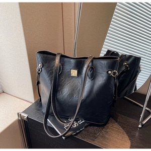 Detail der minimalistischen schwarzen Shopper-Tasche mit goldener Schnalle und Lederstruktur