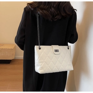 Détail du sac cabas blanc matelassé avec chaîne sombre et fermoir métallique carré