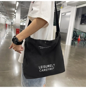 Detail showing high-quality black canvas crossbody bag with white leisure lettering