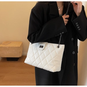Détail de la texture en cuir synthétique matelassé et fermoir métallique du sac blanc
