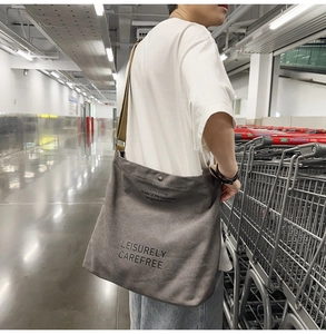 Detail of grey canvas crossbody bag with artistic text and brown shoulder strap
