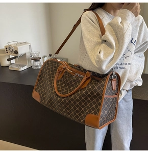 Detail der Reisetasche mit Monogramm-Muster, Ledergriffen und Seitentasche