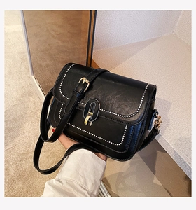 Détail du sac bandoulière noir avec bord perlé blanc et boucle en métal doré