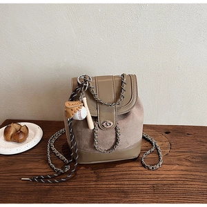 Detailed view of frosted suede bucket backpack with chain strap and baseball pendant