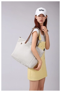 Detail of off-white canvas tote bag with brown handles and external front pocket