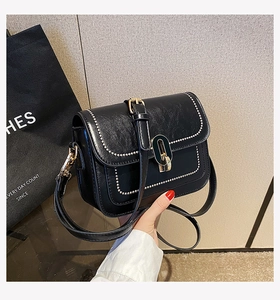 Détail du sac bandoulière noir avec bordure en perles argentées et fermoir ovale doré