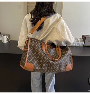 Detail einer großen braunen Stepp-Reisetasche mit Ledergriffen und breitem Schultergurt