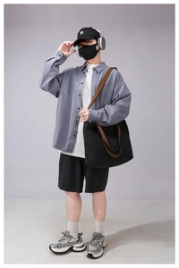 Detailed view of model wearing a black canvas tote bag with a blue utility shirt