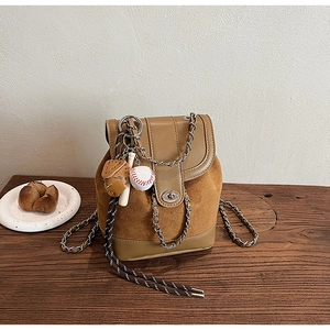 Close-up of frosted brown backpack with baseball charm and metal chain strap detailing