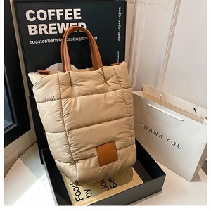 Close-up of quilted puff tote bag with premium brown leather handles in a gift box