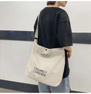 Detailed view of cream canvas crossbody bag featuring Leisurely Carefree art lettering