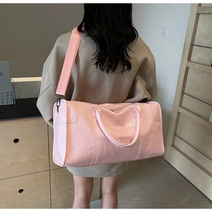 Vista trasera de un gran bolso de viaje rosa brillante con logo MOCO en una modelo mujer