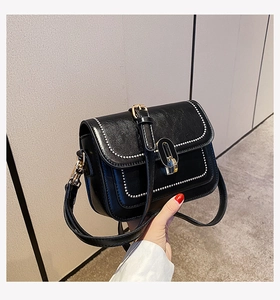 Détail du sac carré en similicuir noir avec fermoir doré et bordure à pois blancs