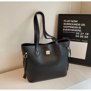 Detail der minimalistischen schwarzen Shopper-Tasche mit goldenen Beschlägen und Kordelzug