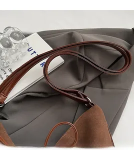 Detail of slim brown leather strap and matte suede texture on vintage shoulder bag