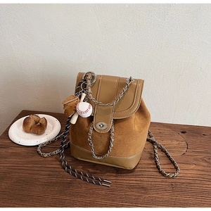 Detail of tan matte leather bag with metal twist lock, chain strap, and baseball charms