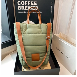 Detail of sage green quilted puffer tote bag with brown leather handles in gift box