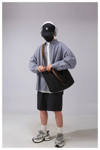 Detail of a black canvas tote bag with brown straps worn by a model for a casual look