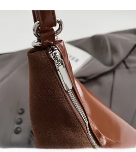 Detail of silver smooth metal zipper on brown textured tote bag with mixed leather finish
