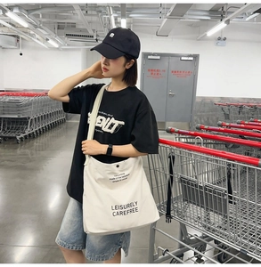 White canvas messenger bag with Leisurely Carefree print shown in a street style look