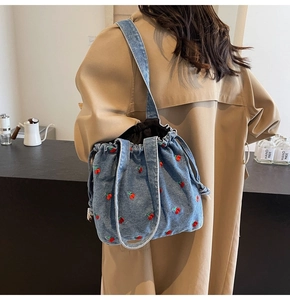 Detailed view of denim bucket bag with cherry embroidery and drawstring closure