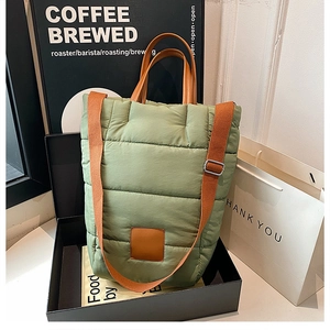 Quilted green bucket bag with brown handles and strap shown in a vintage cafe setting