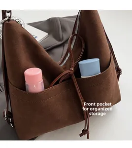 Detail of front pockets on brown suede shoulder bag showing large storage capacity
