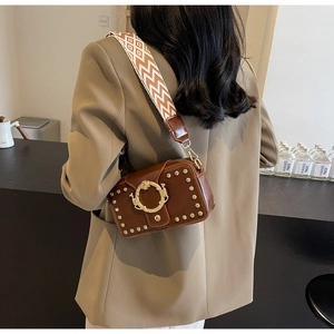 Detailansicht der dunkelbraunen Ledertasche mit Vintage-Nieten und gewebtem Jacquard-Gurt