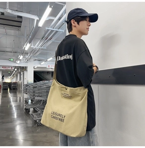 Close-up of khaki canvas shoulder bag with black LEISURELY CAREFREE text print