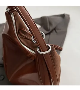 Detail of silver metal ring hardware and brown suede leather texture on a tote bag