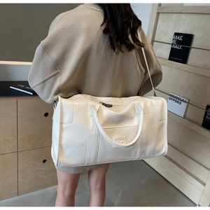 Detalle del bolso de viaje NOCO marfil con textura brillante plisada y asas reforzadas
